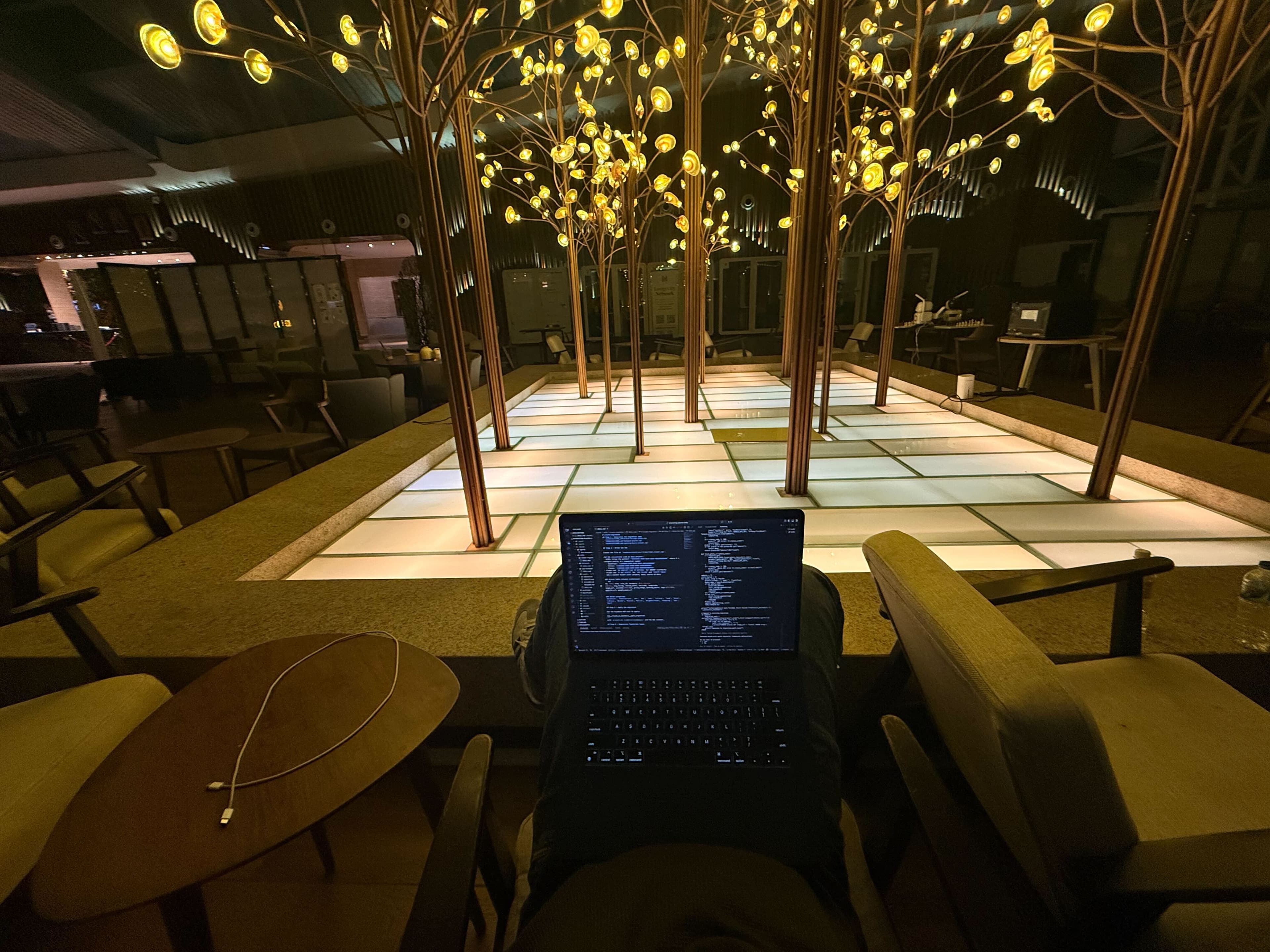 Laptop open in a moody lounge with light-up trees